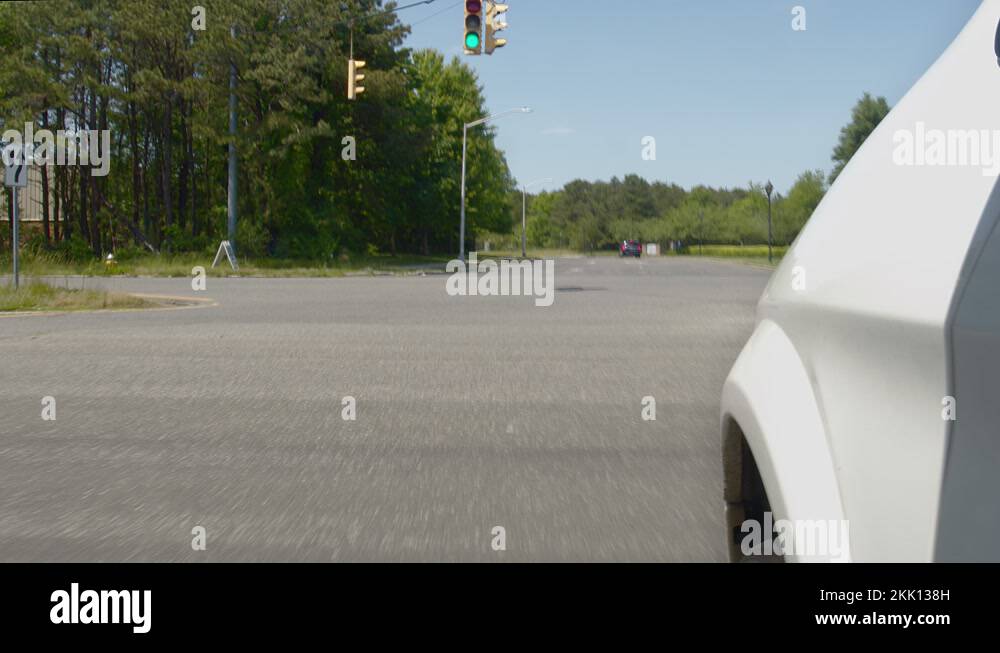 During the day, a white car turns left when a traffic light turns green
