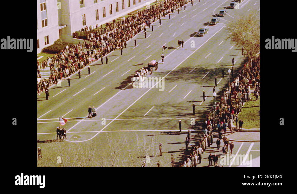 1960s Horses pull carriage with casket down road in funeral procession