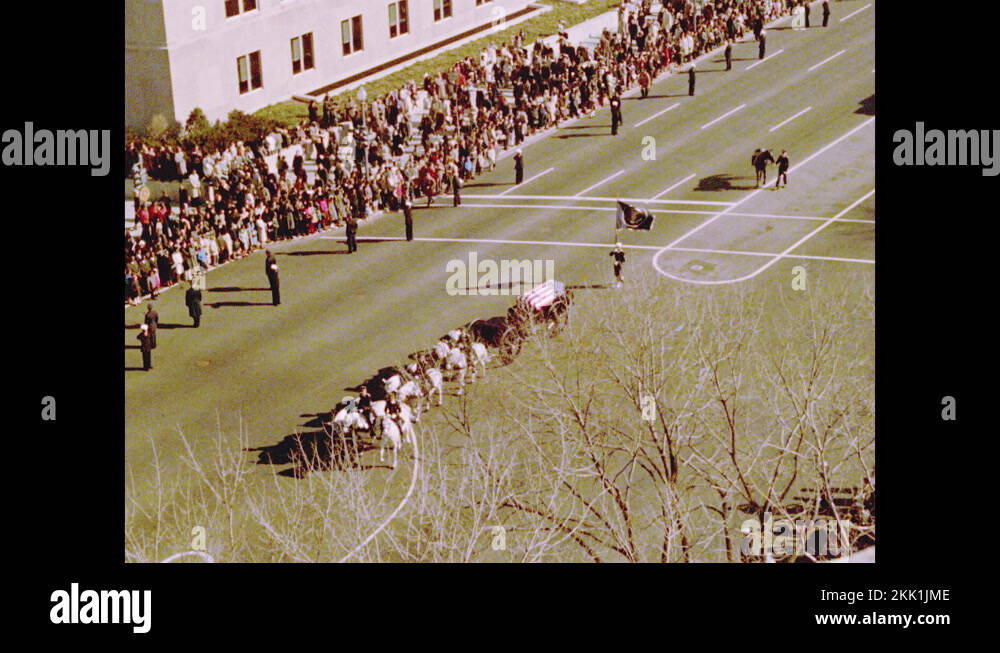 1960s Horses pull carriage with casket down road in funeral procession