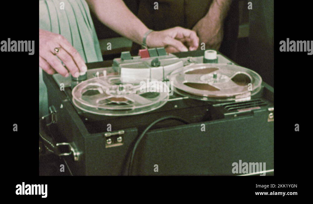1960s Girl turns on turntable and reel to reel tape recorder. Teacher