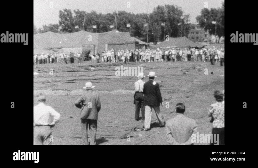 1940s Elephant hoists circus tent poles upright as large crowd looks