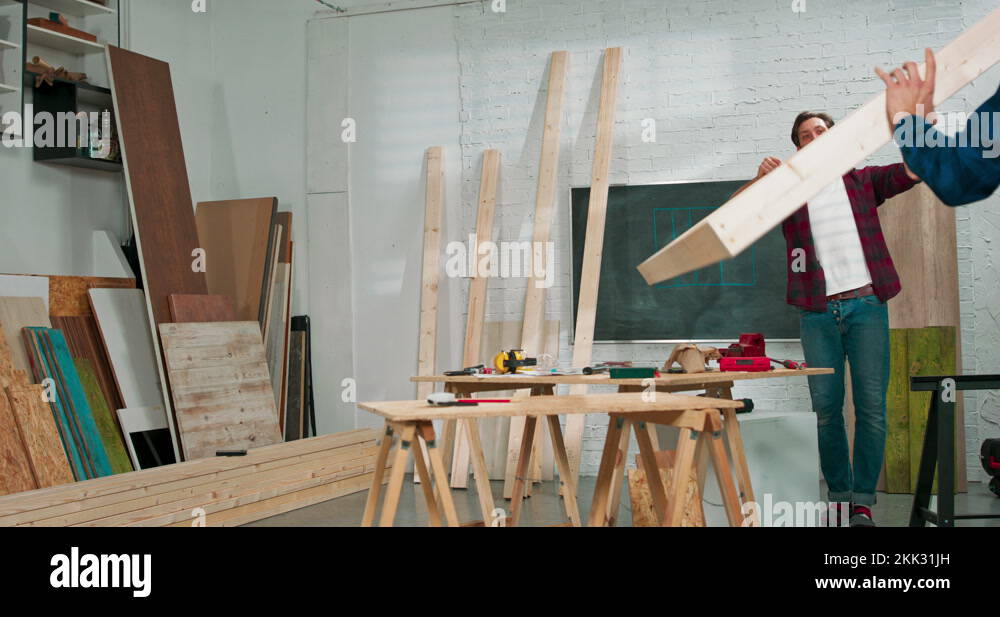 Young carpenters build a solid wood wall in a carpentry The