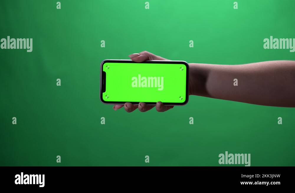 Woman hand holding the smartphone on green screen chroma key background ...