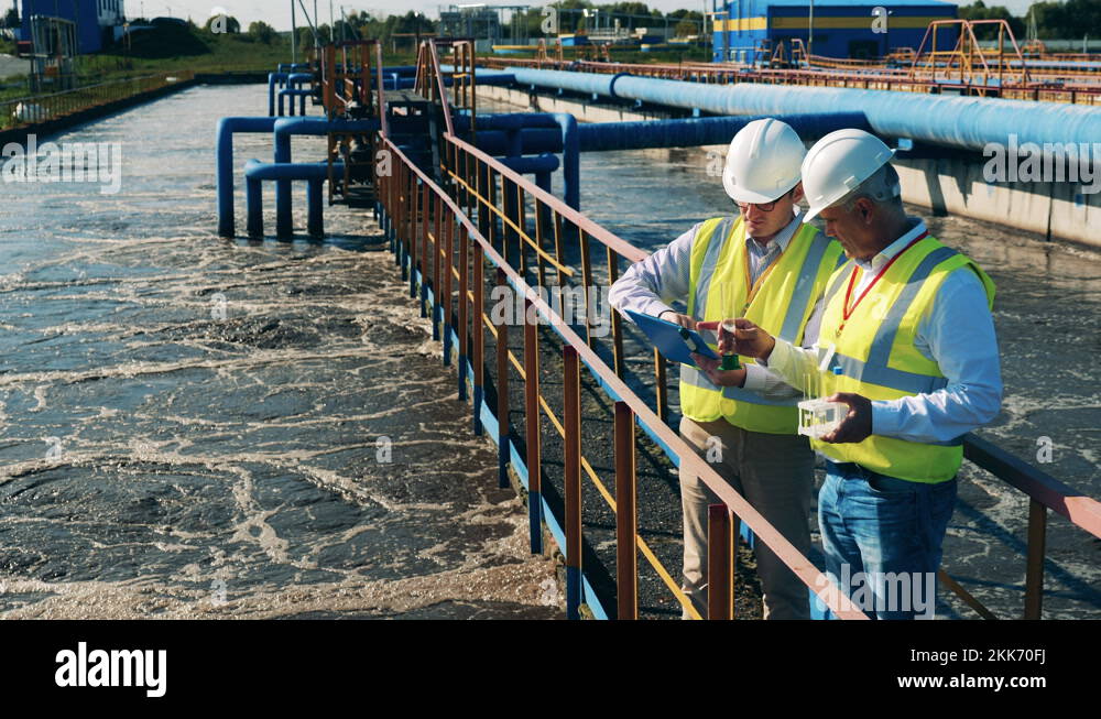 Wastewater operators checking water condition at a sewage treatment