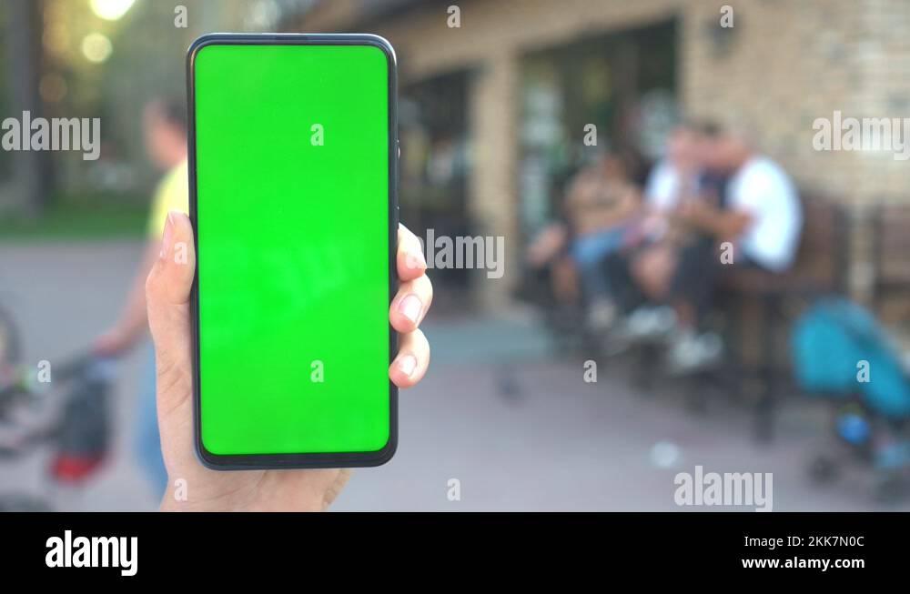 Close up hands woman holding phone with vertical green screen on busy ...
