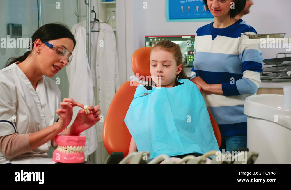 Dentist explaining to girl procedure of extraction using model of