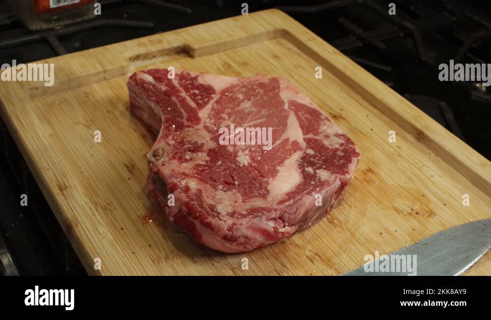 Seasoning a Rib eye steak with salt and pepper Stock Video Footage Alamy