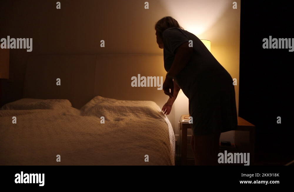 Single older woman lying in bed under blanket at night, lady going to