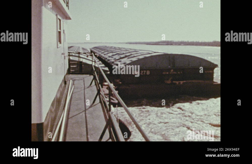 1970s: Loaded barge in bay. Person piloting barge. Barge in canal ...