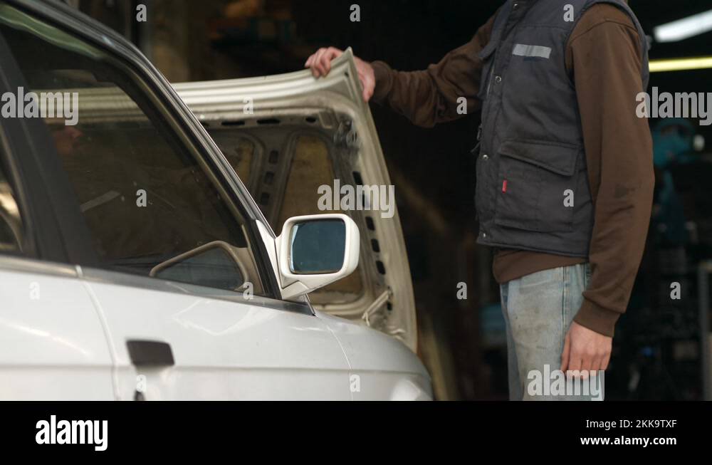 Mechanic walks up to old white car, lifts hood, and looks inside Stock Video Footage Alamy