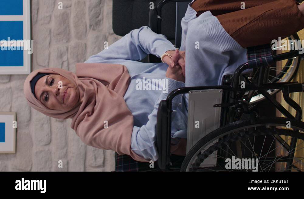 Sad disabled woman with turban in a wheelchair alone in the living room at home Stock Video