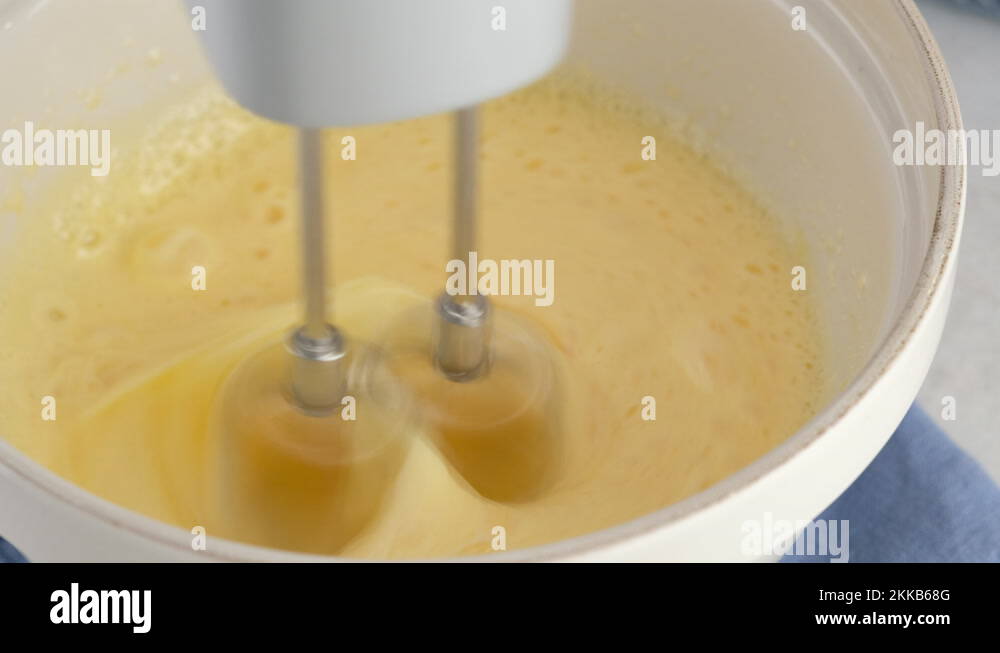 Closeup mixing egg whites, yolks and sugar in a ceramic bowl with a