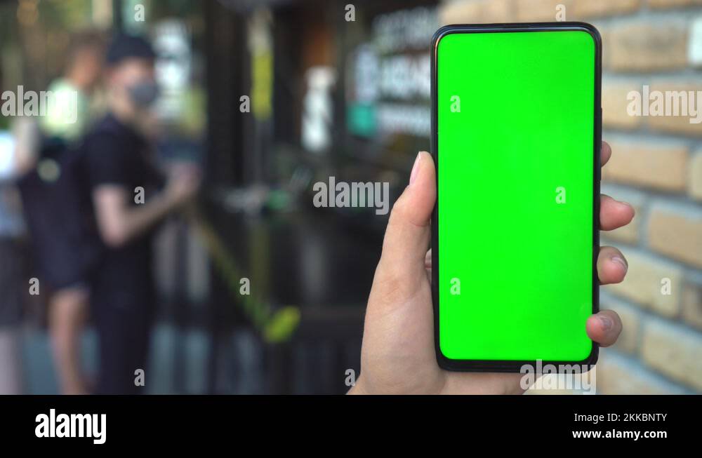 Close up hands woman holding phone with vertical green screen on busy ...
