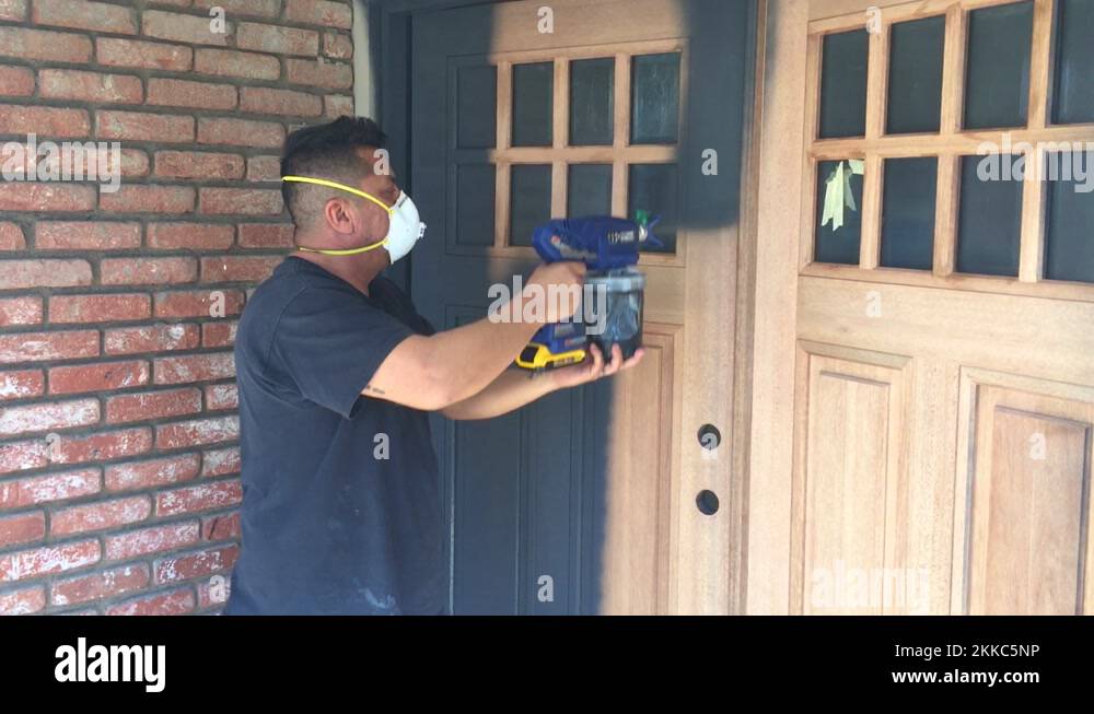 Professional painter applying wood primer to wood doors with spray gun