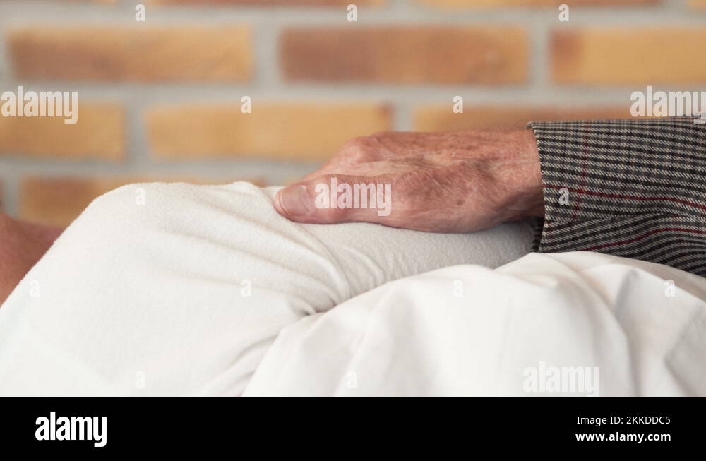 Elderly husband hand rubbing on arm of wife lying in bed, close up ...