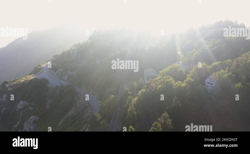 Drone camera follows an electric car driving fast up a narrow road in the Stock Video Footage