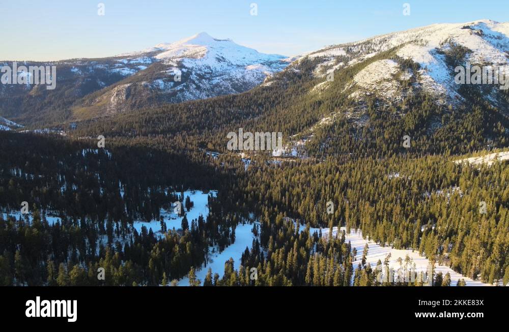 Drone birdseye footage over ski slopes and surrounding alpine forest on