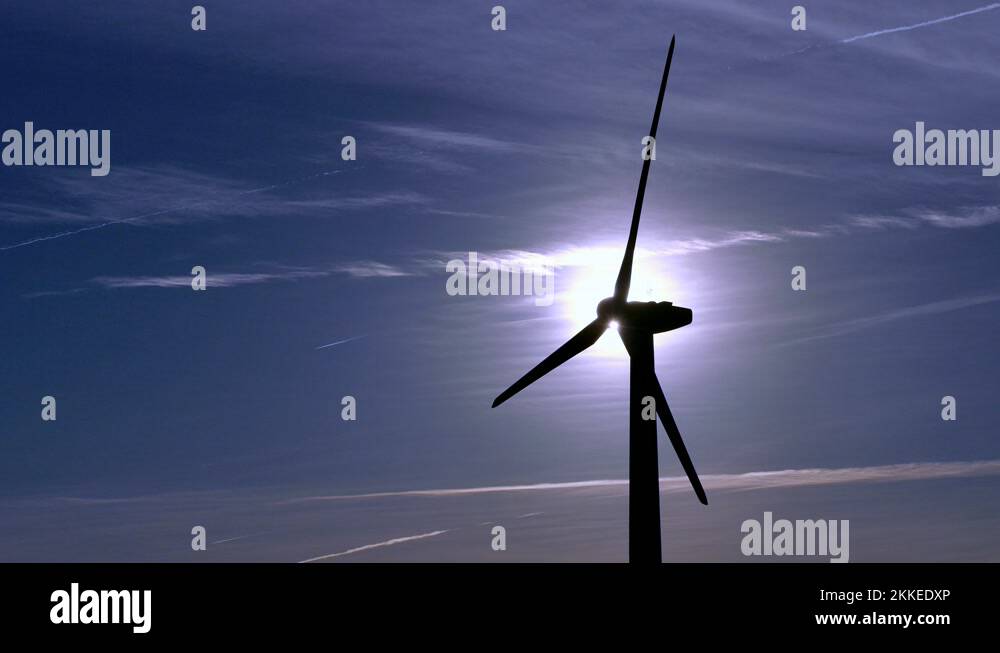 Spinning turbine blades at wind farm blue background clouds clean