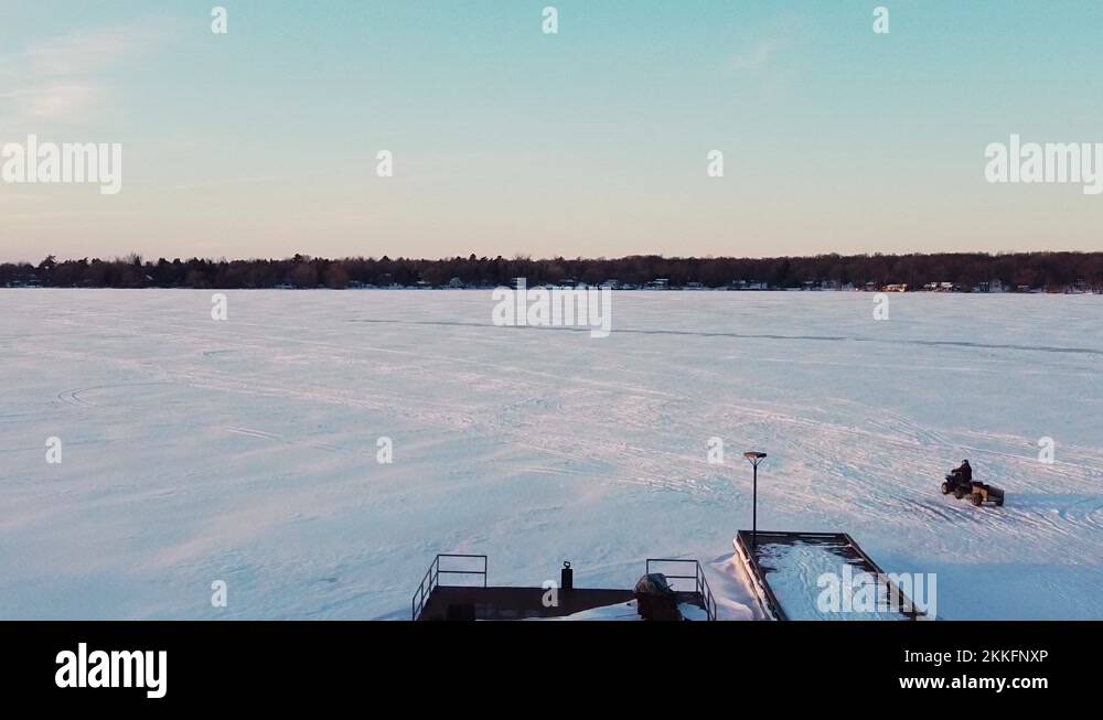 Fourwheeler ATV driving on frozen snow covered lake road during sunset