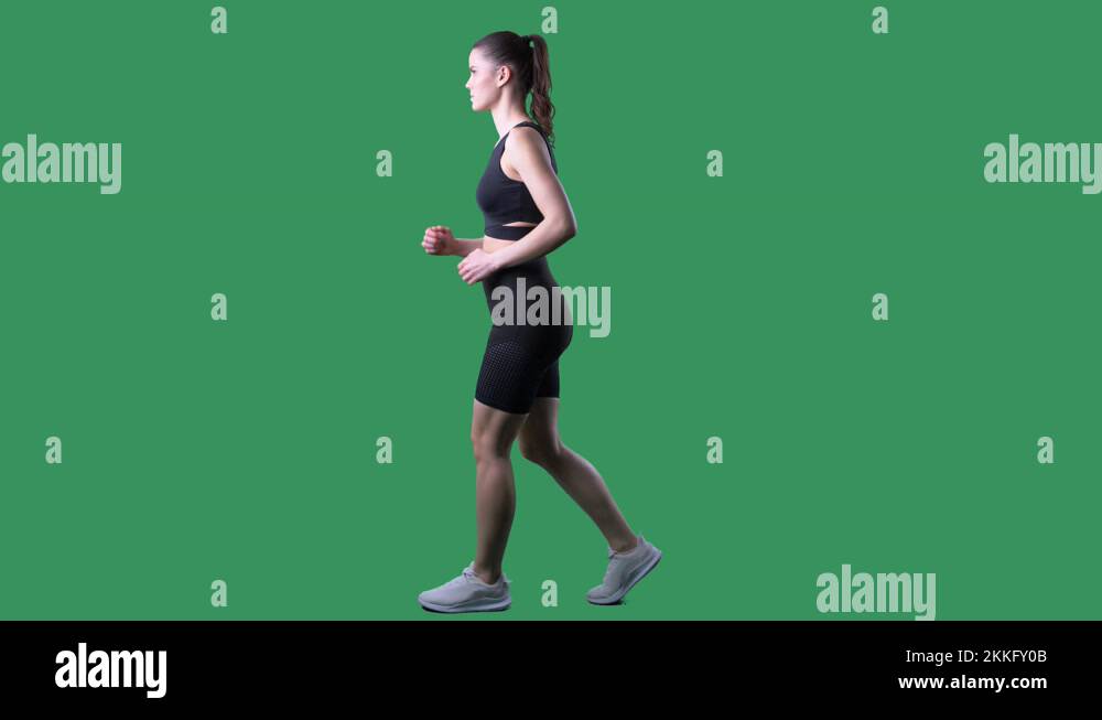 Slow motion side view of fit woman speed walking. Full body on green