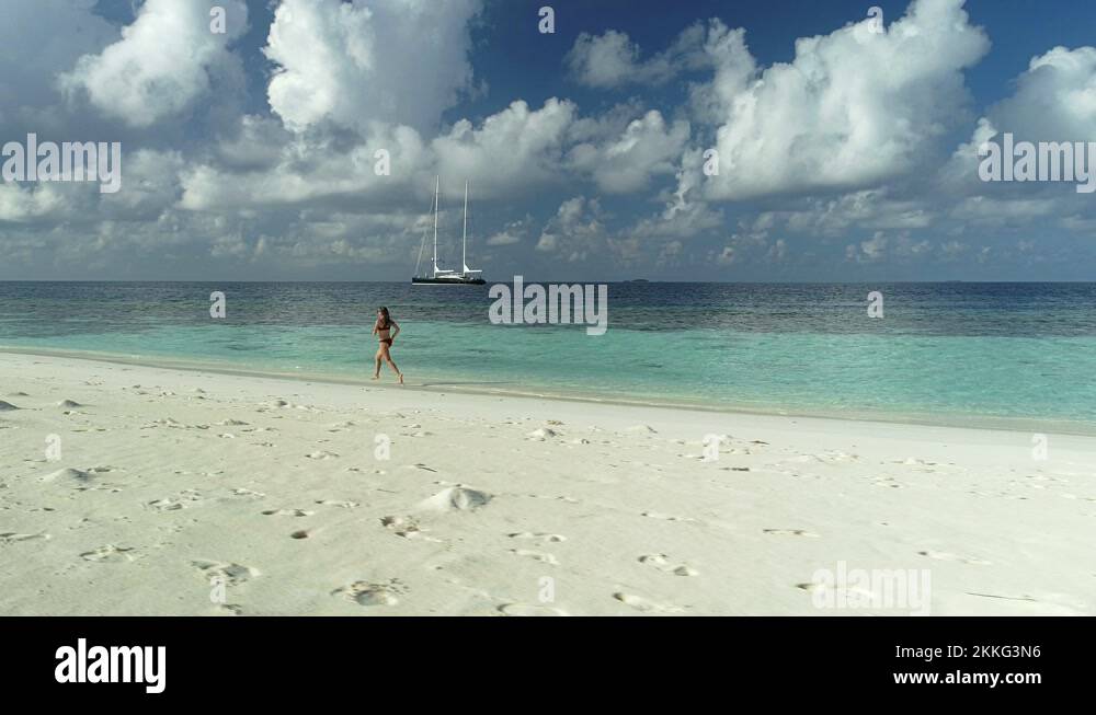 Girl in a red bikini jogging along the edge of the ocean Stock Video