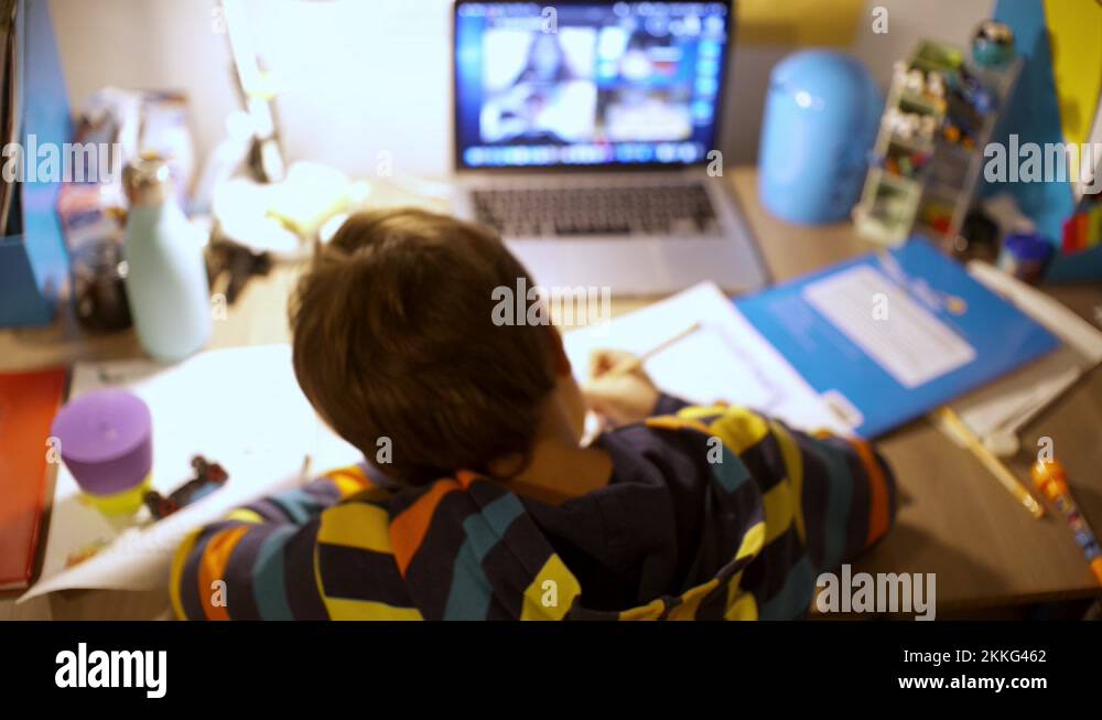 Back view of caucasian six year's old boy, studying at his desk with