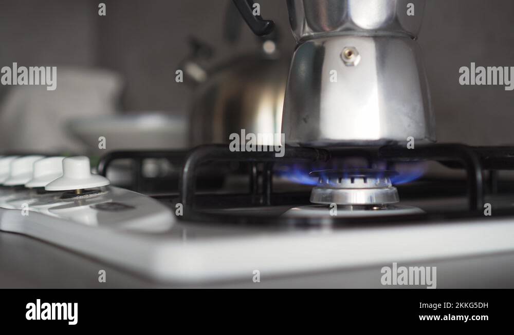Gas stove with blue flames and coffee in moke pot, turning on by hand