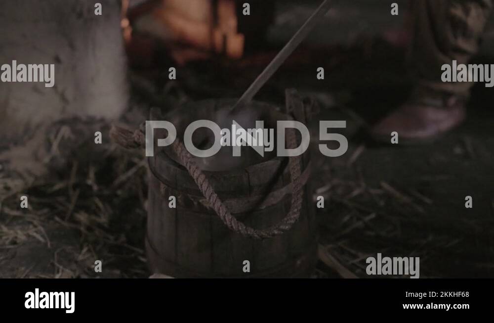 Hot metal rod dipped in water held in antique wooden bucket with rope