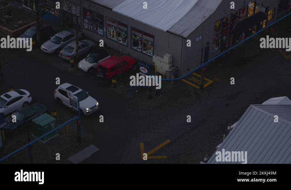 a quiet evening of a white Car leaving parking lot at the back alley of