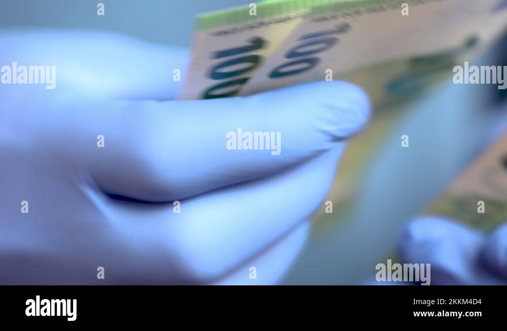 Hands with blue protective medical gloves are counting 100 EURO money