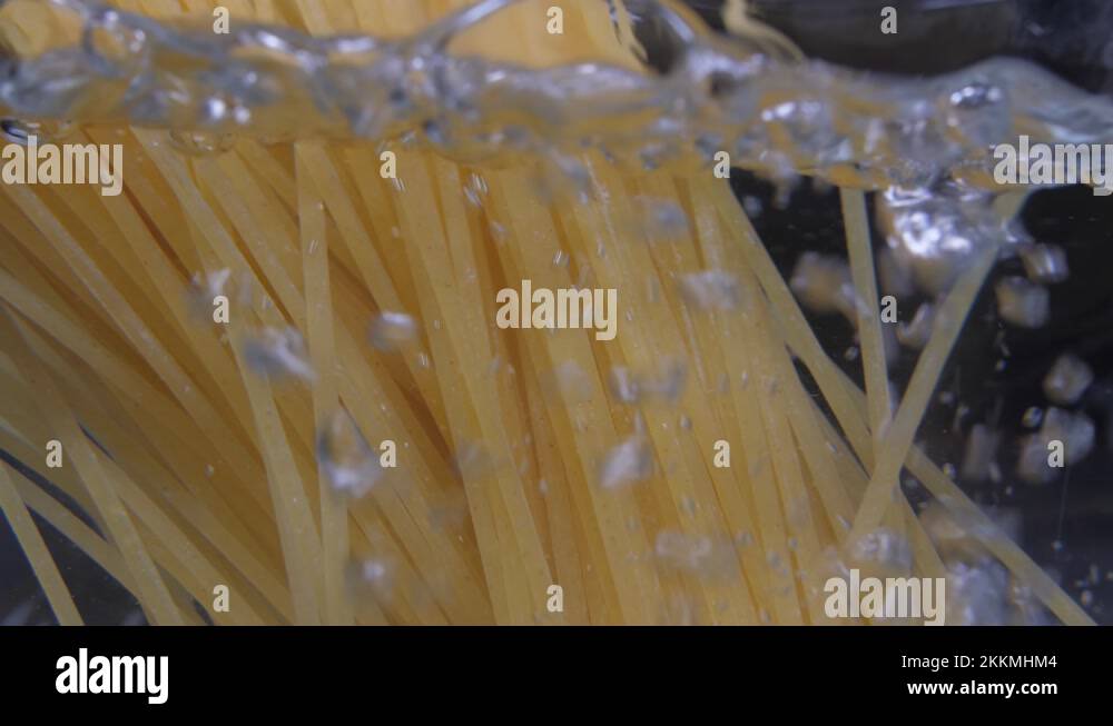 pouring spaghetti pasta into pot with boiling water slow motion 4k
