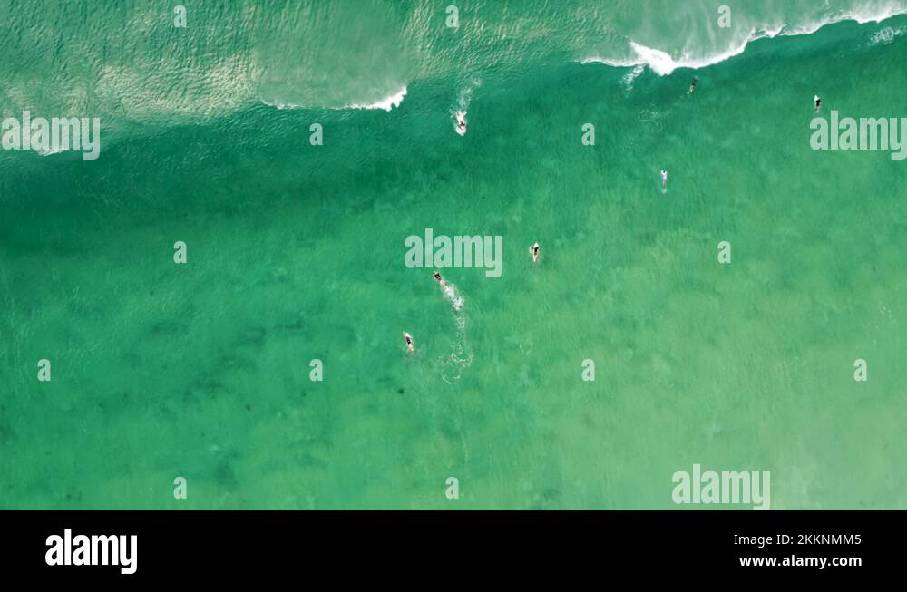 Sky drone shot over ocean waves with surfing and bodyboarding duck dive