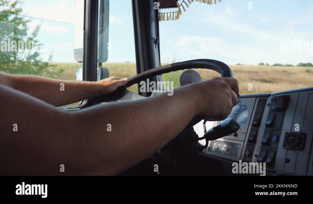 Male arms of lorry driver holds a big steering wheel while operating a