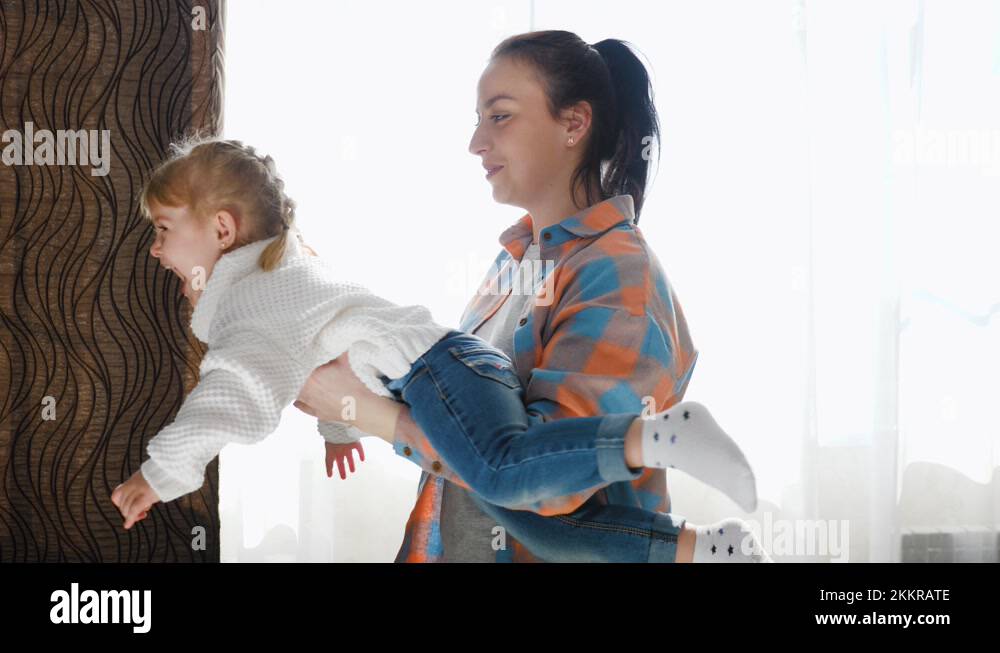 Mom plays with child, daughter is circling in her arms, cute baby is