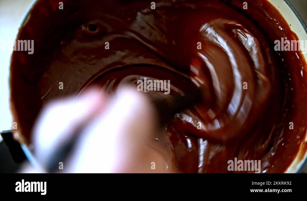 Cooking and stirring a chocolate frosting, spread or topping on a stove