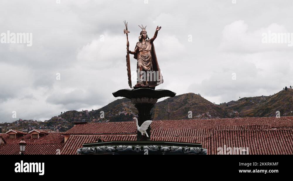 Golden Atahualpa statue in Main plaza cuzco with roofs and mountains