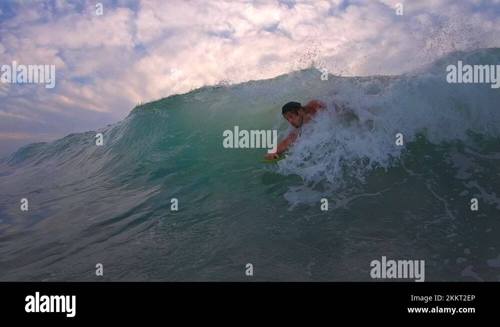 Bodysurfing with handplane. Young man surfs the ocean wave with