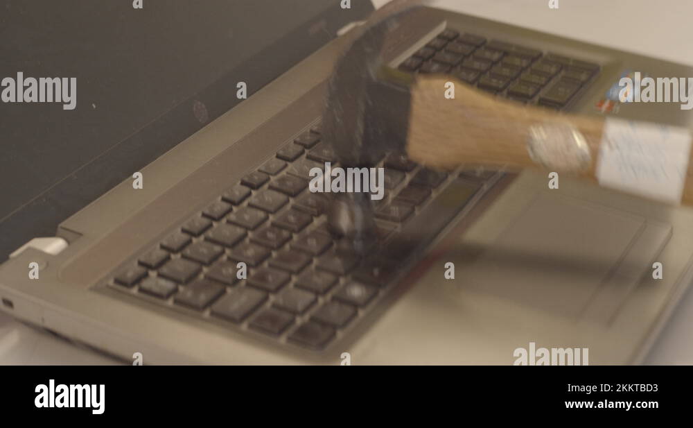 Slow motion. Smashing laptop keyboard by hitting with a hammer. Angry