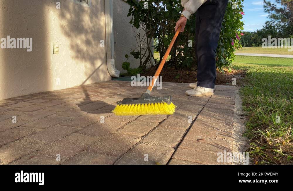 Man sweeping brick paver stone porch with push broom Stock Video