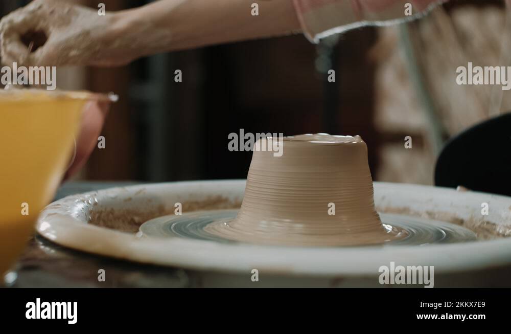 Potter shapes the clay product with pottery tools on the potter's wheel