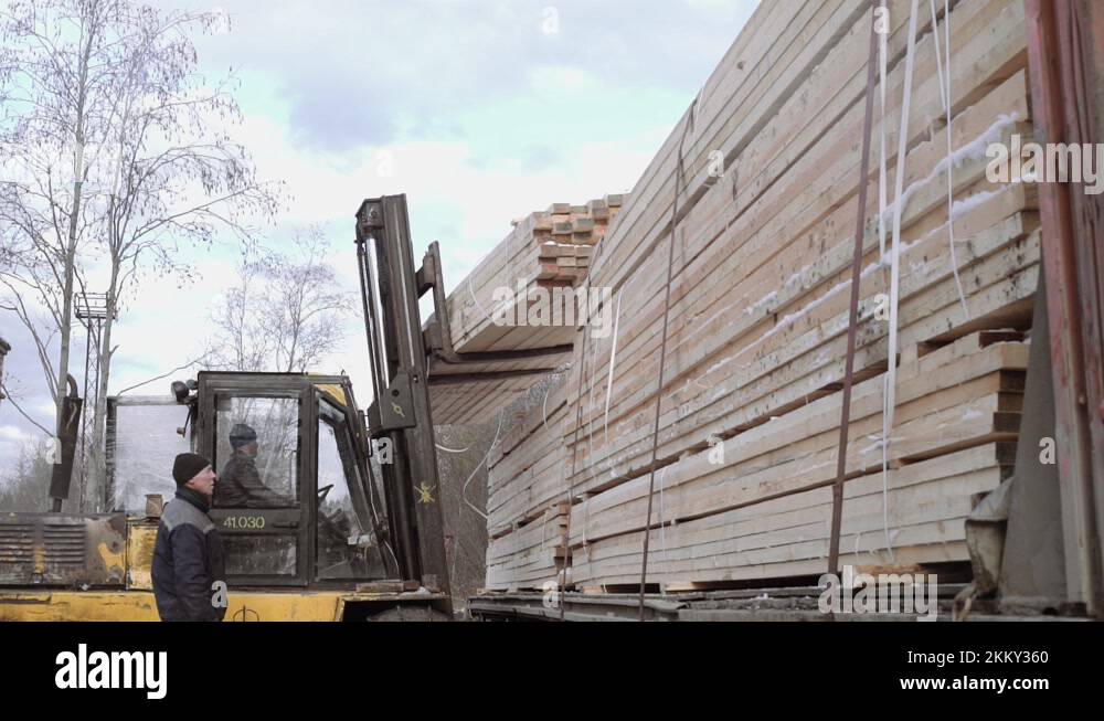 Forklift load packs of lumber boards on heavy truck at sawmill factory