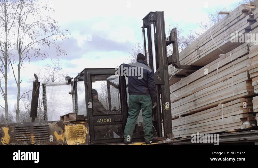 Forklift load stack of lumber boards on heavy truck at sawmill factory