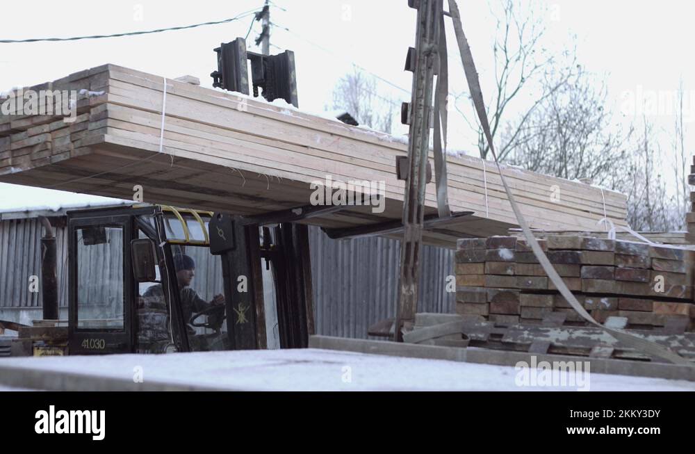 Forklift driver and workers straightening board stack on lorry loader ...