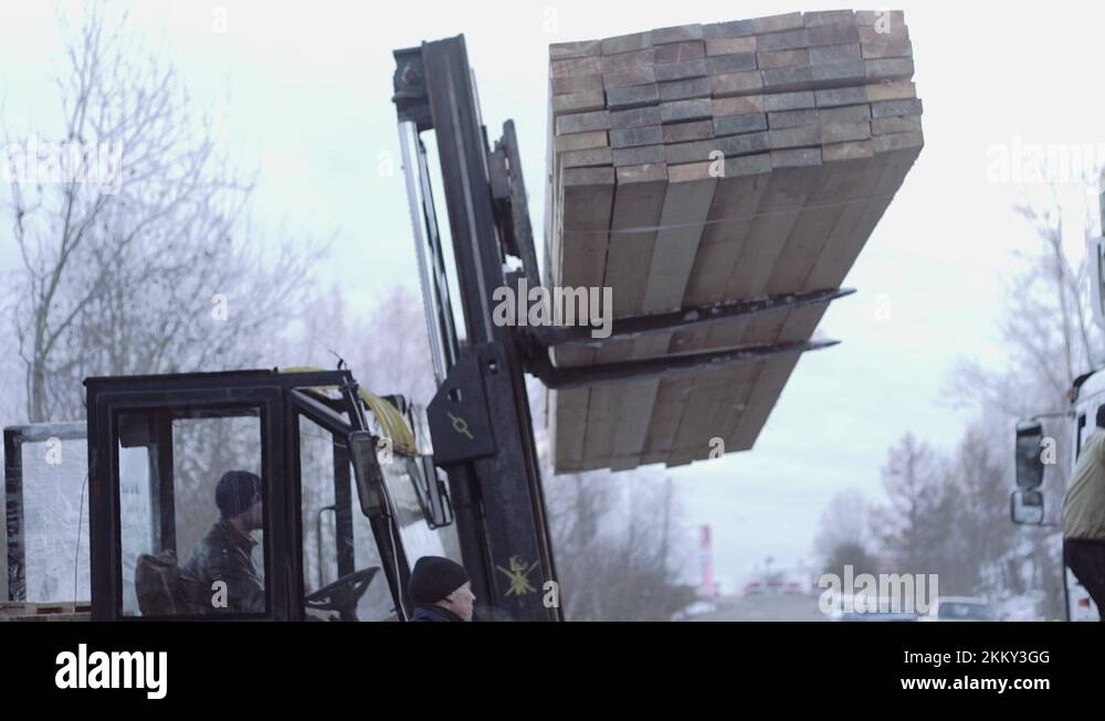 Forklift load packs of lumber boards on lorry truck at sawmill factory