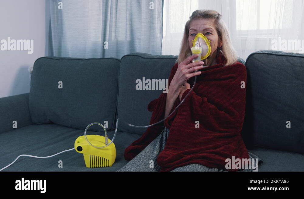 old woman wrapped in blanket using oxygen inhaler at home Stock Video