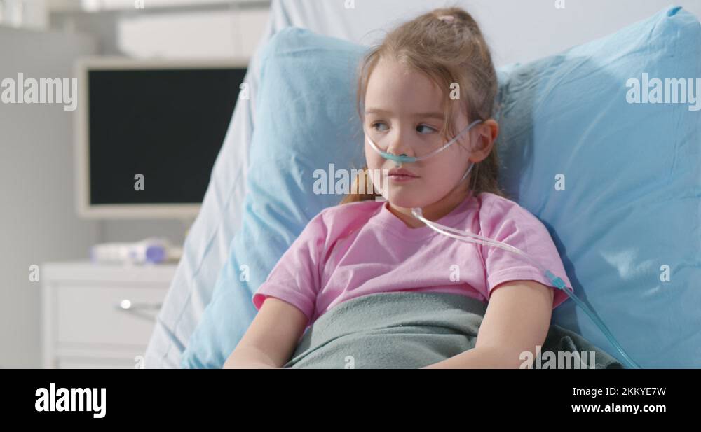 Girl suffering from pneumonia lying in hospital bed with oxygen nasal