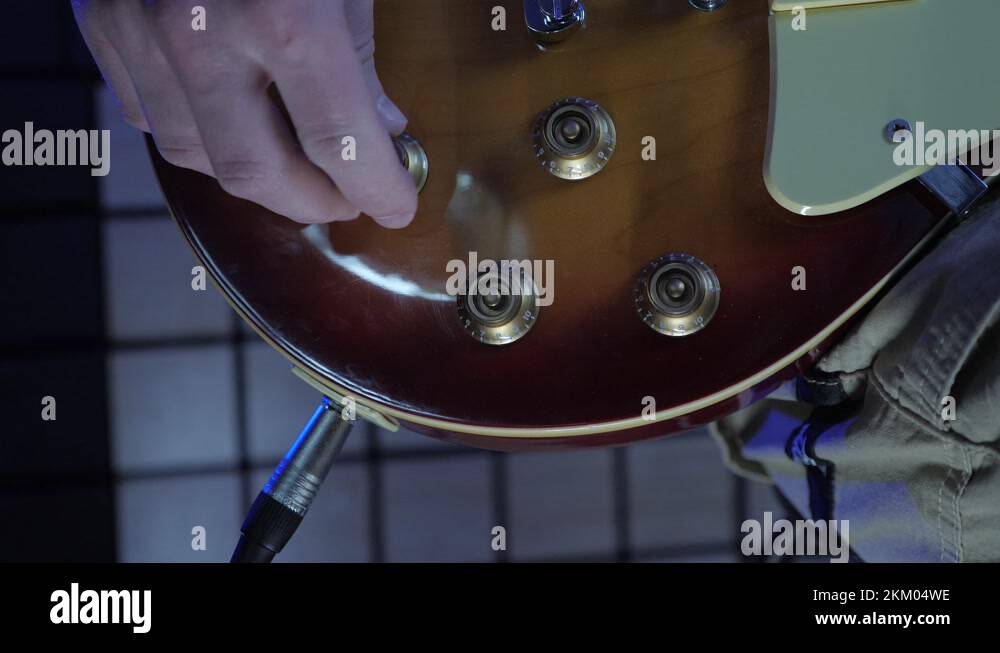 Turning volume and tone knobs on electric guitar at sound record studio