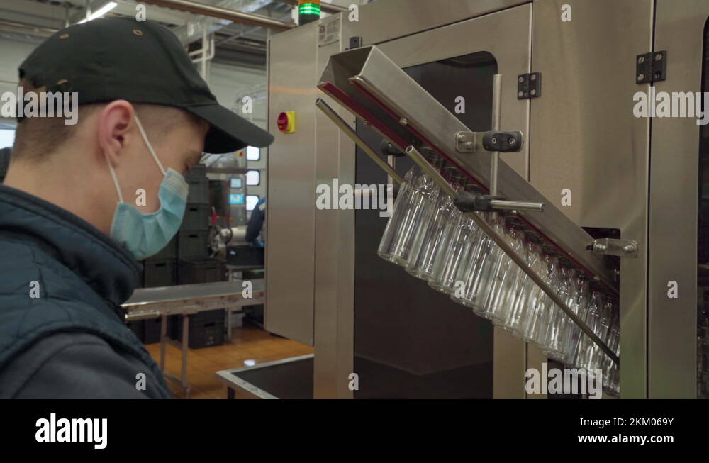 Machine with a conveyor. Operator loads plastic bottles in a moving conveyor Stock Video Footage