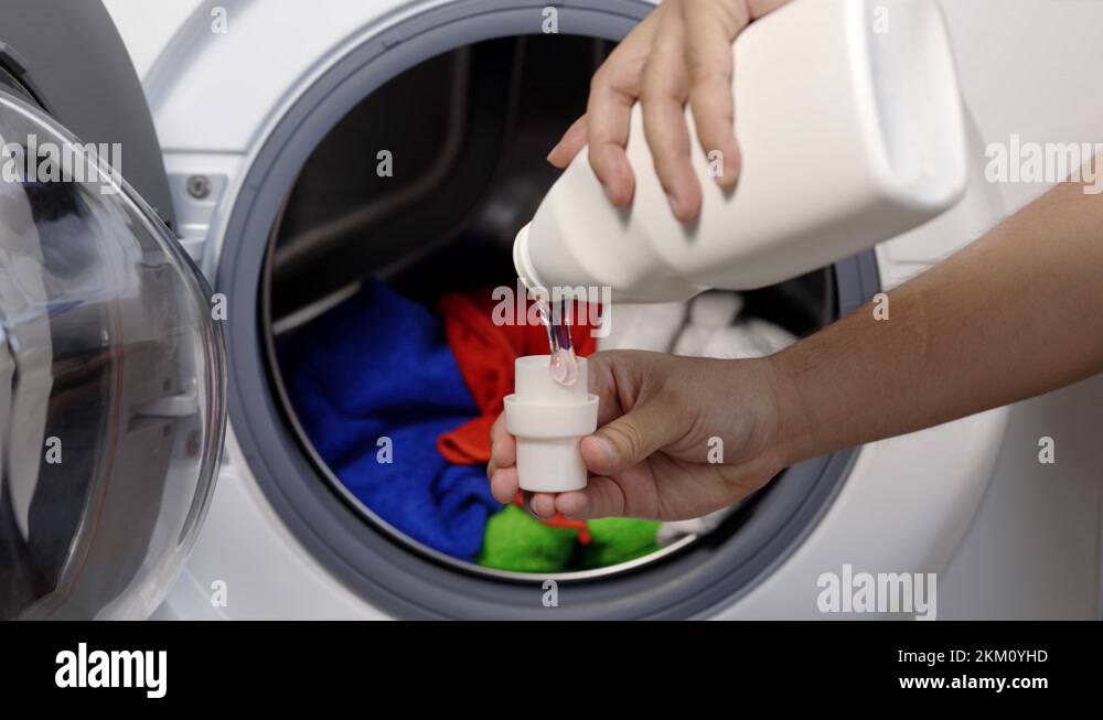 Pour some laundry detergent on the clothes and put it in the washing machine Stock Video Footage