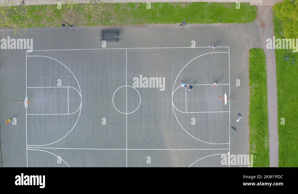 Full basketball court top down aerial shot. Male players shoot baskets